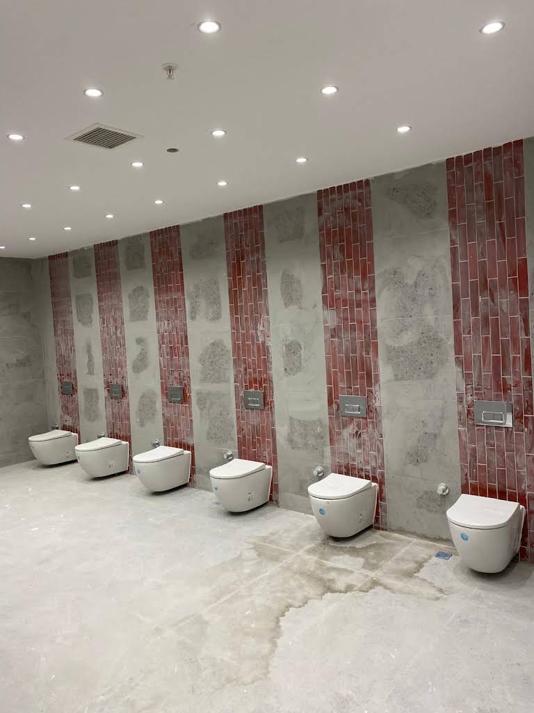 Gri ve kırmızı duvar seramikleri ile vitrifiye elemanları